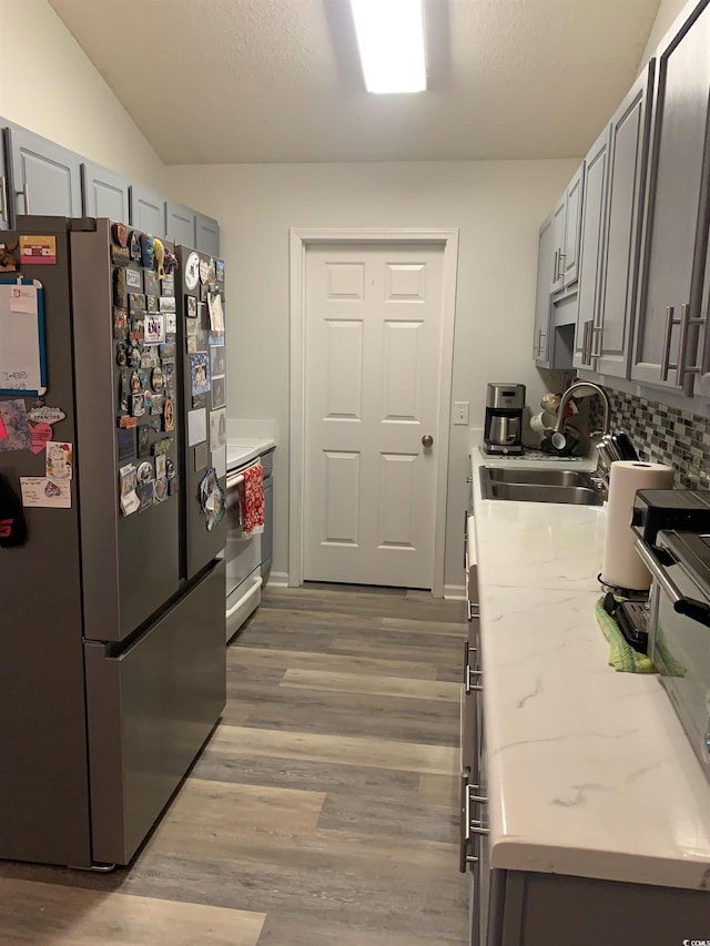 kitchen with stainless steel refrigerator, sink, gray cabinetry, and light hardwood / wood-style floors