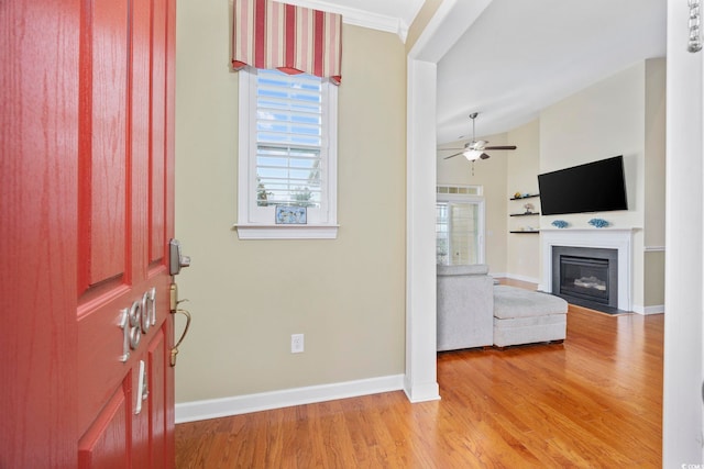 foyer featuring lofted ceiling, a fireplace with flush hearth, a ceiling fan, light wood-type flooring, and baseboards