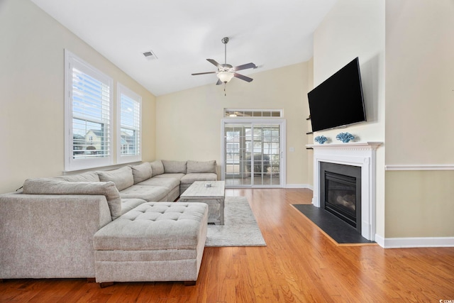 living room with a fireplace with flush hearth, a healthy amount of sunlight, visible vents, and wood finished floors