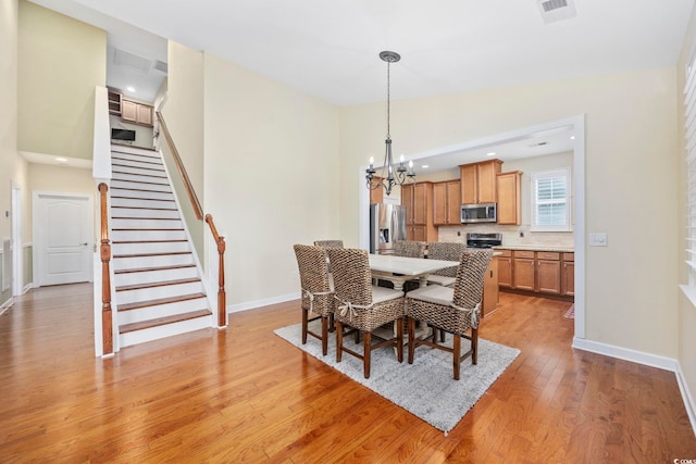 dining space with a chandelier, visible vents, baseboards, stairs, and light wood finished floors