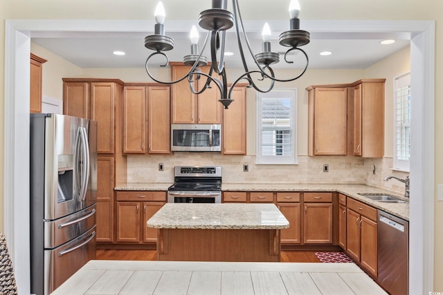 kitchen with tasteful backsplash, an inviting chandelier, appliances with stainless steel finishes, a sink, and a kitchen island