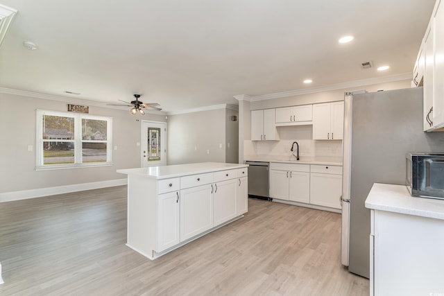 kitchen featuring ceiling fan, appliances with stainless steel finishes, a center island, light hardwood / wood-style floors, and white cabinets