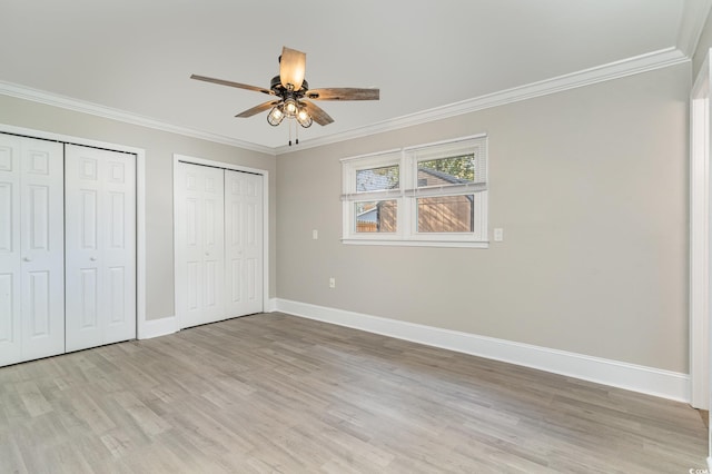 unfurnished bedroom with multiple closets, ornamental molding, ceiling fan, and light wood-type flooring