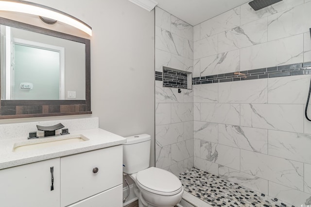 bathroom featuring vanity, toilet, and tiled shower