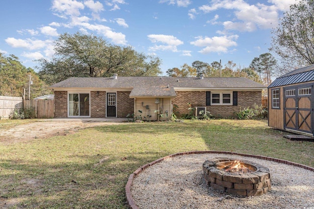 back of property featuring central AC unit, a yard, a storage unit, and an outdoor fire pit