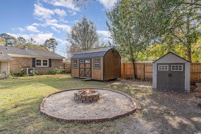 view of yard with a storage shed, an outdoor fire pit, and central air condition unit