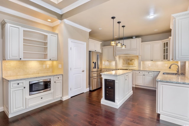 kitchen featuring white cabinets, a kitchen island, stainless steel appliances, pendant lighting, and a sink