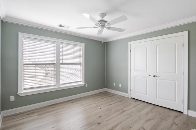 unfurnished bedroom with baseboards, visible vents, crown molding, light wood-type flooring, and a closet