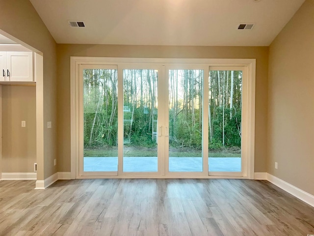 doorway to outside featuring light wood-type flooring and vaulted ceiling