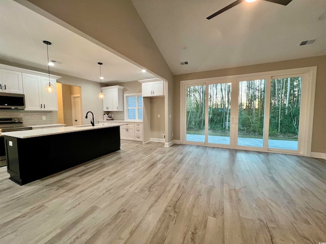 kitchen featuring white cabinetry, stainless steel appliances, light hardwood / wood-style flooring, vaulted ceiling, and decorative light fixtures