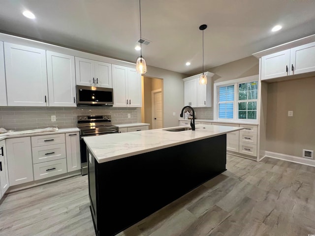 kitchen featuring white cabinets, a center island with sink, light hardwood / wood-style flooring, decorative light fixtures, and stainless steel appliances