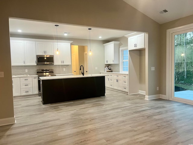 kitchen featuring white cabinetry, an island with sink, light hardwood / wood-style floors, decorative light fixtures, and appliances with stainless steel finishes