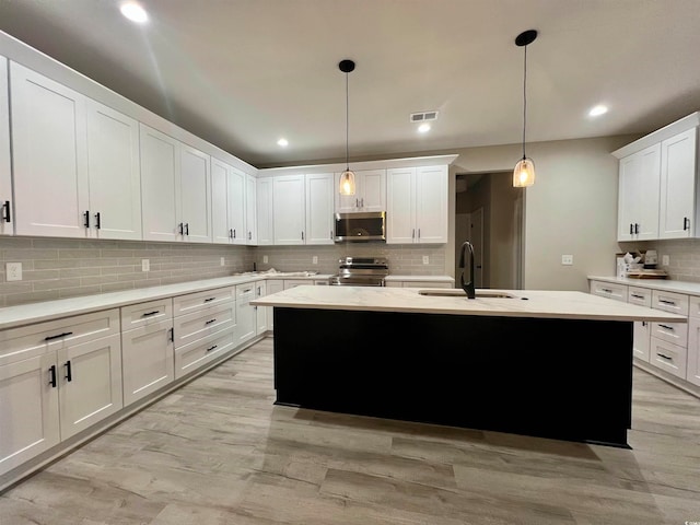 kitchen featuring appliances with stainless steel finishes, tasteful backsplash, sink, decorative light fixtures, and white cabinetry