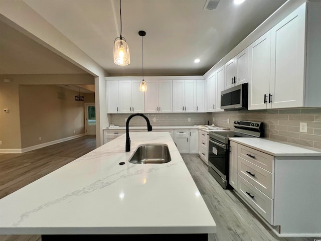 kitchen with white cabinetry, sink, light hardwood / wood-style flooring, a center island with sink, and appliances with stainless steel finishes