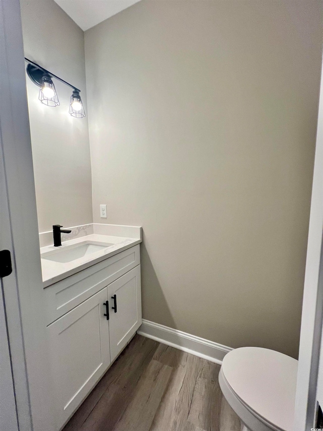 bathroom with toilet, vanity, and hardwood / wood-style flooring