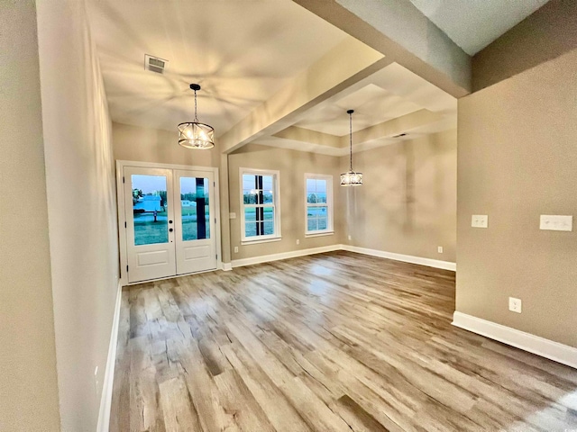 foyer entrance with hardwood / wood-style floors, a chandelier, and french doors