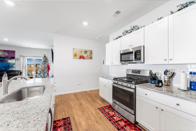 kitchen with white cabinets, appliances with stainless steel finishes, light hardwood / wood-style floors, and sink