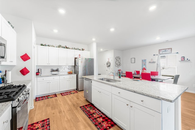 kitchen featuring an island with sink, stainless steel appliances, white cabinetry, and sink