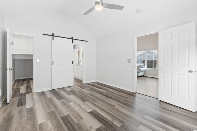 140 Wimbledon Way Unit 140, Murrells Inlet, SC 29576 - unfurnished bedroom with a barn door, wood finished floors, a walk in closet, vaulted ceiling, and baseboards