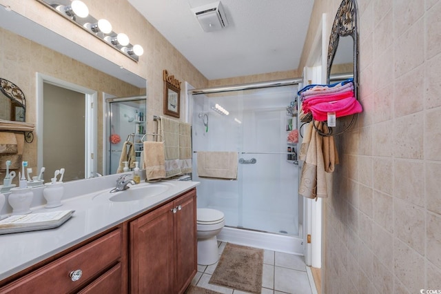 bathroom with vanity, tile patterned floors, a shower with door, and tile walls