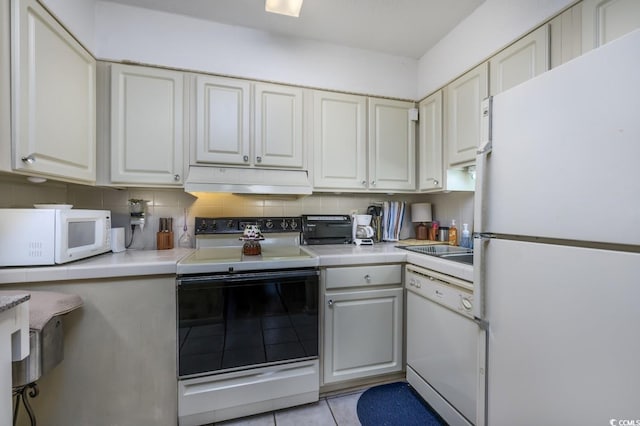 kitchen with white cabinetry, white appliances, backsplash, and light tile patterned floors