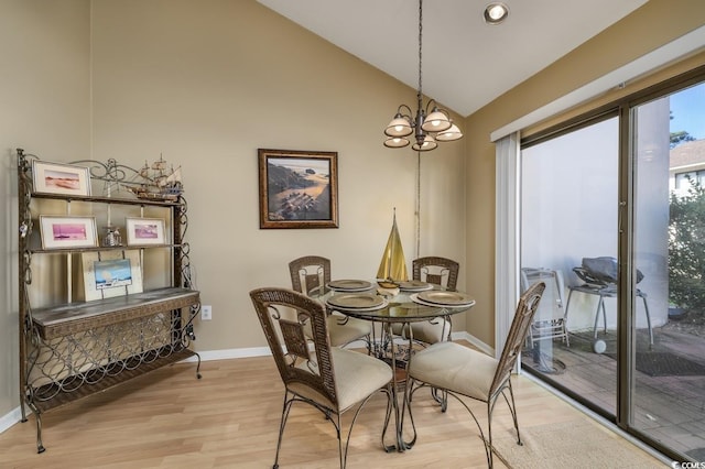 dining space featuring light wood-type flooring, high vaulted ceiling, and an inviting chandelier