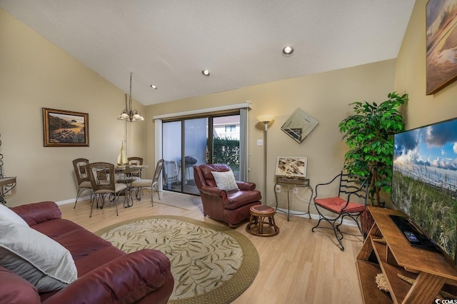 living room featuring a textured ceiling, light hardwood / wood-style floors, an inviting chandelier, and high vaulted ceiling