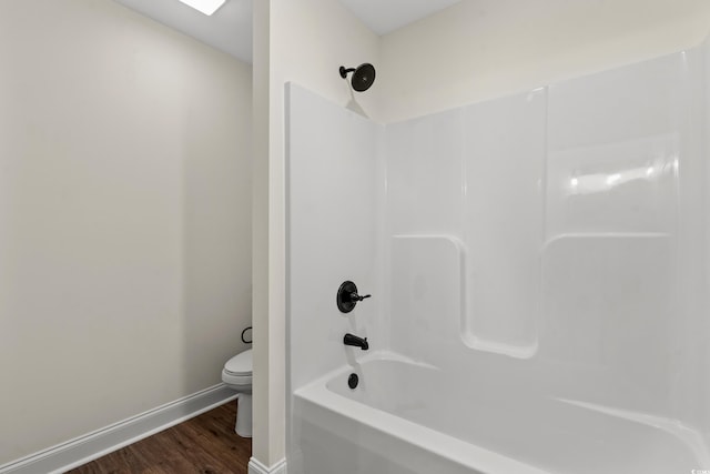 bathroom featuring toilet, wood-type flooring, and tub / shower combination