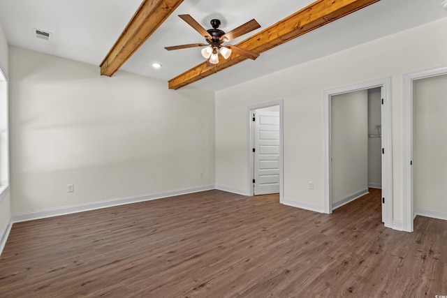 unfurnished bedroom featuring beamed ceiling, dark hardwood / wood-style floors, ceiling fan, and a spacious closet