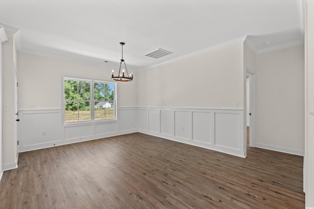 spare room featuring crown molding, dark wood-type flooring, and a chandelier