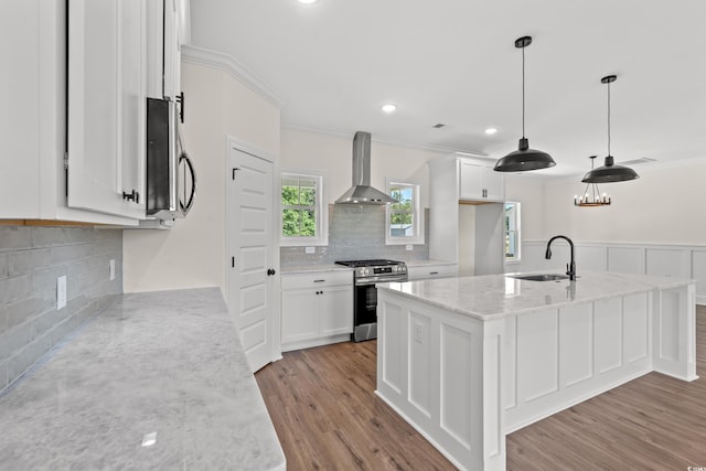 kitchen featuring sink, wall chimney exhaust hood, light stone counters, white cabinets, and appliances with stainless steel finishes