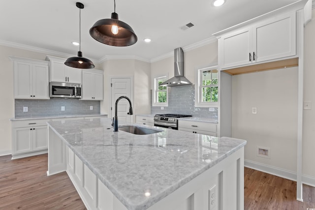 kitchen with white cabinets, sink, hanging light fixtures, wall chimney exhaust hood, and stainless steel appliances