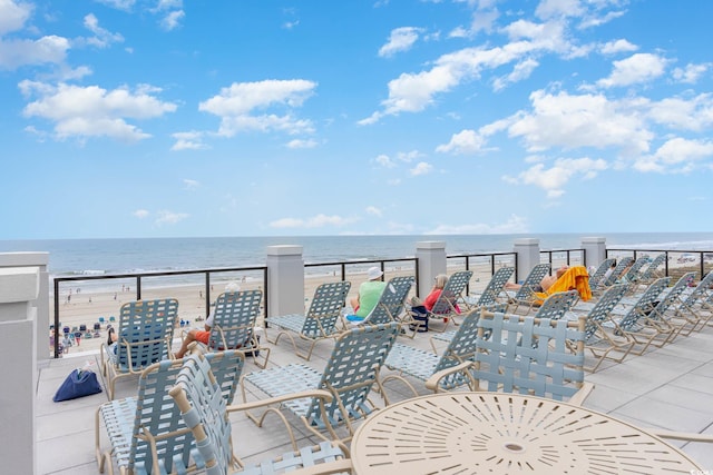 view of patio with a balcony, a water view, and a beach view