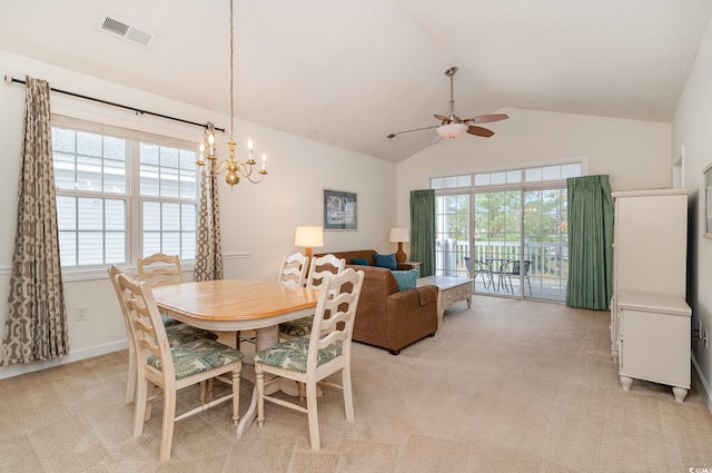 dining room with ceiling fan with notable chandelier, a healthy amount of sunlight, light colored carpet, and vaulted ceiling