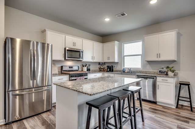 kitchen with white cabinetry, a center island, light hardwood / wood-style flooring, and appliances with stainless steel finishes