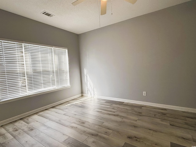 spare room featuring ceiling fan, light hardwood / wood-style floors, and a textured ceiling