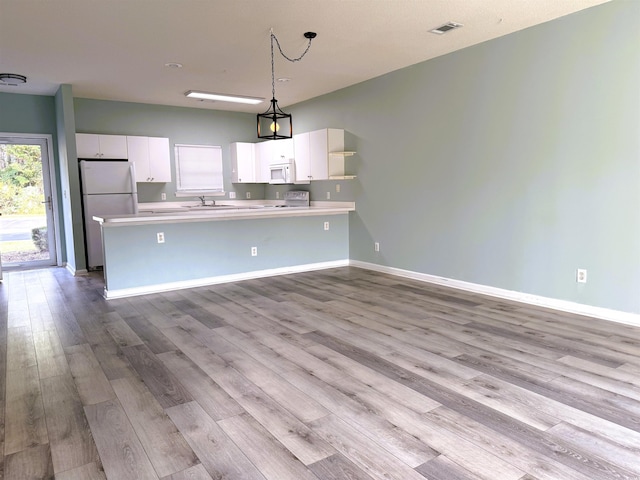 kitchen featuring white appliances, hanging light fixtures, light wood-type flooring, white cabinetry, and kitchen peninsula