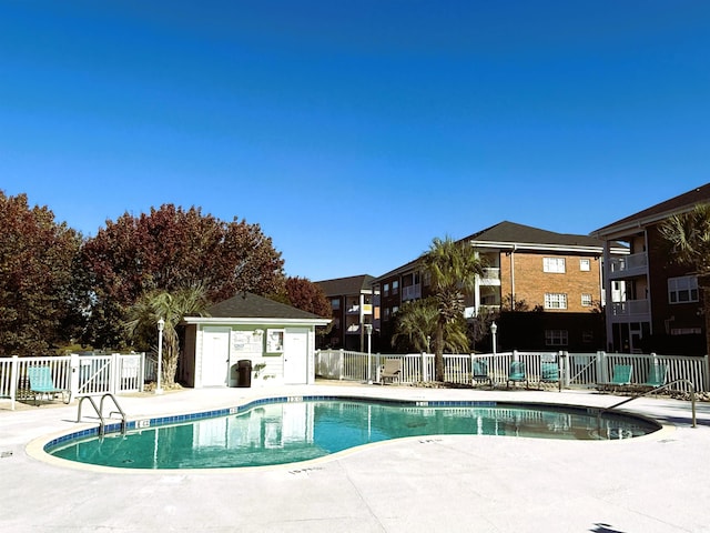 view of swimming pool featuring an outbuilding and a patio