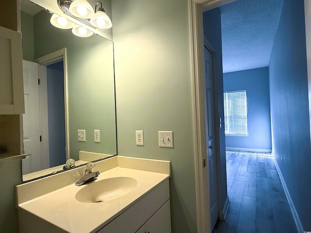 bathroom featuring vanity, wood-type flooring, and a textured ceiling