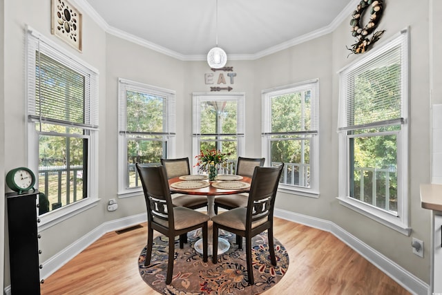 dining area with hardwood / wood-style floors, plenty of natural light, and crown molding