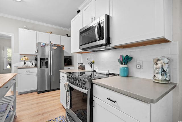 kitchen with stainless steel appliances, light hardwood / wood-style floors, decorative backsplash, white cabinets, and ornamental molding