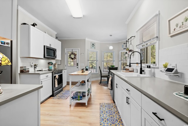 kitchen with white cabinetry, sink, tasteful backsplash, appliances with stainless steel finishes, and light wood-type flooring