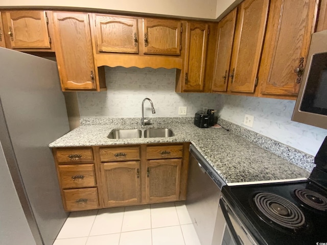 kitchen with light stone counters, sink, light tile patterned flooring, and stainless steel appliances