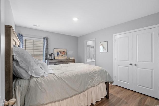 bedroom featuring hardwood / wood-style flooring, ensuite bath, and a closet