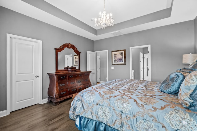 bedroom with a raised ceiling, dark hardwood / wood-style flooring, and an inviting chandelier