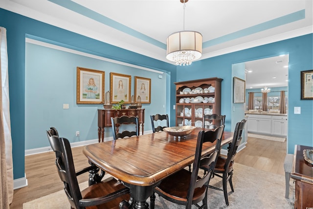 dining space with light hardwood / wood-style floors and an inviting chandelier