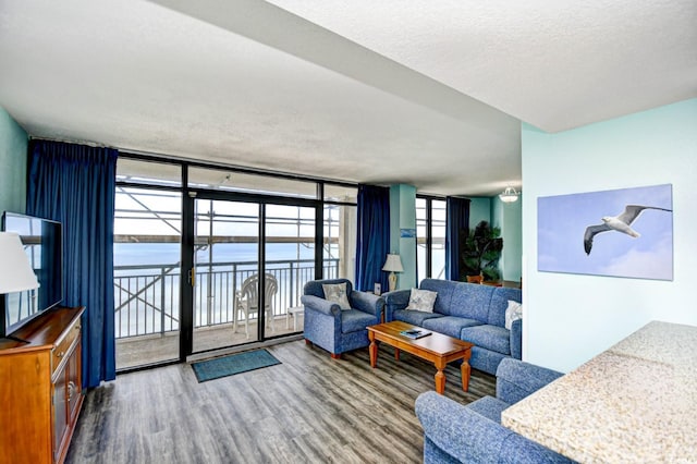 living room with plenty of natural light, a water view, a wall of windows, and wood-type flooring