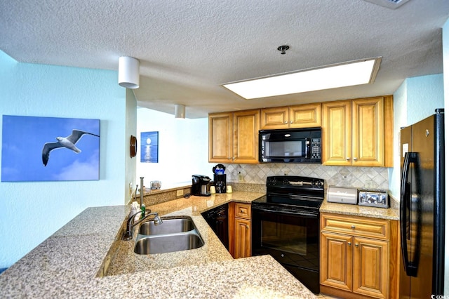 kitchen featuring black appliances, sink, decorative backsplash, light stone countertops, and kitchen peninsula