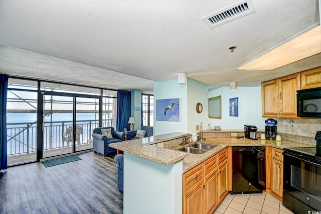 kitchen featuring kitchen peninsula, a textured ceiling, sink, and black appliances