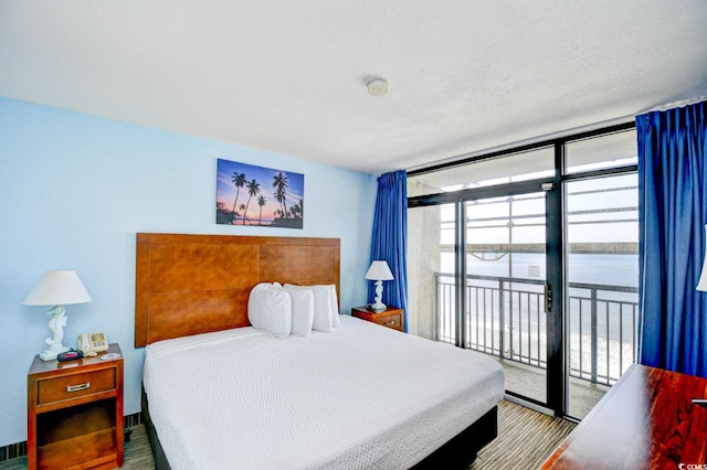 bedroom featuring access to outside, expansive windows, and a water view